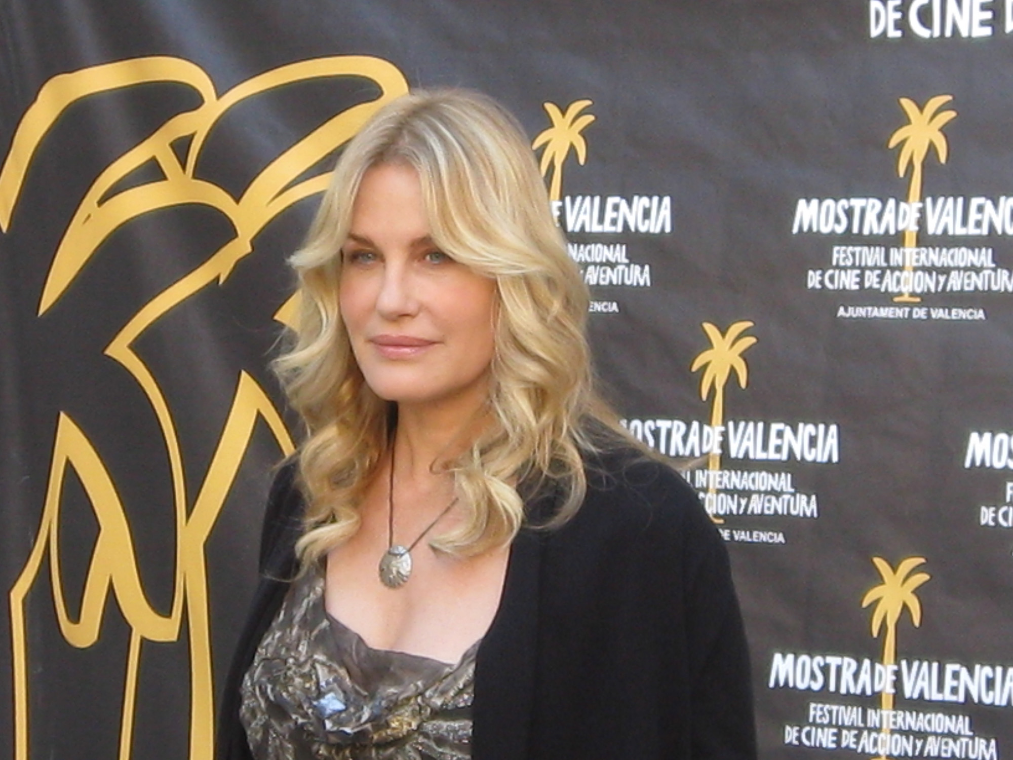 The actress Daryl Hannah is standing in front of a backdrop that promotes the event she is attending.