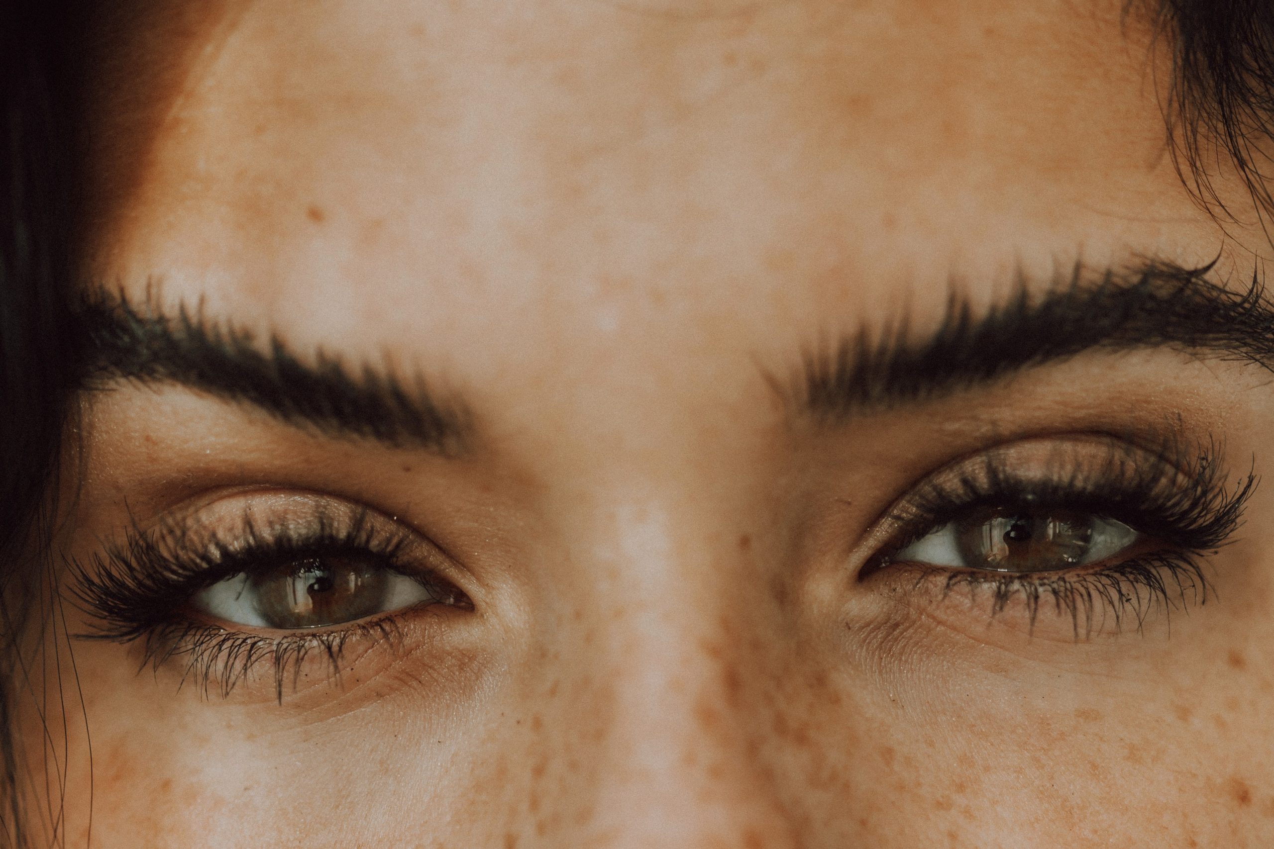 A close-up of a woman's forehead, eyebrows, eyes and the top part of her nose