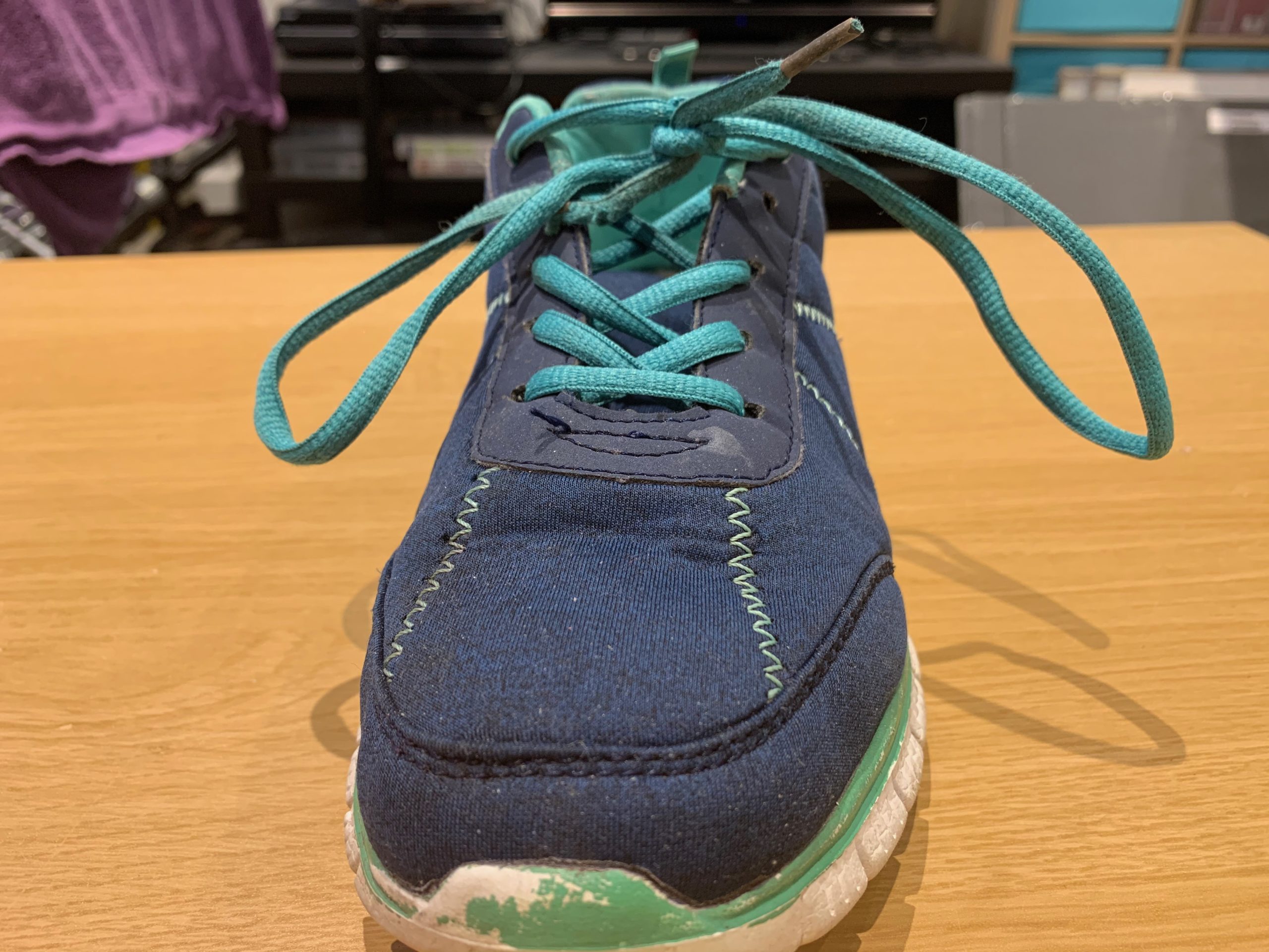 A navy and teal trainer with its laces done up.
