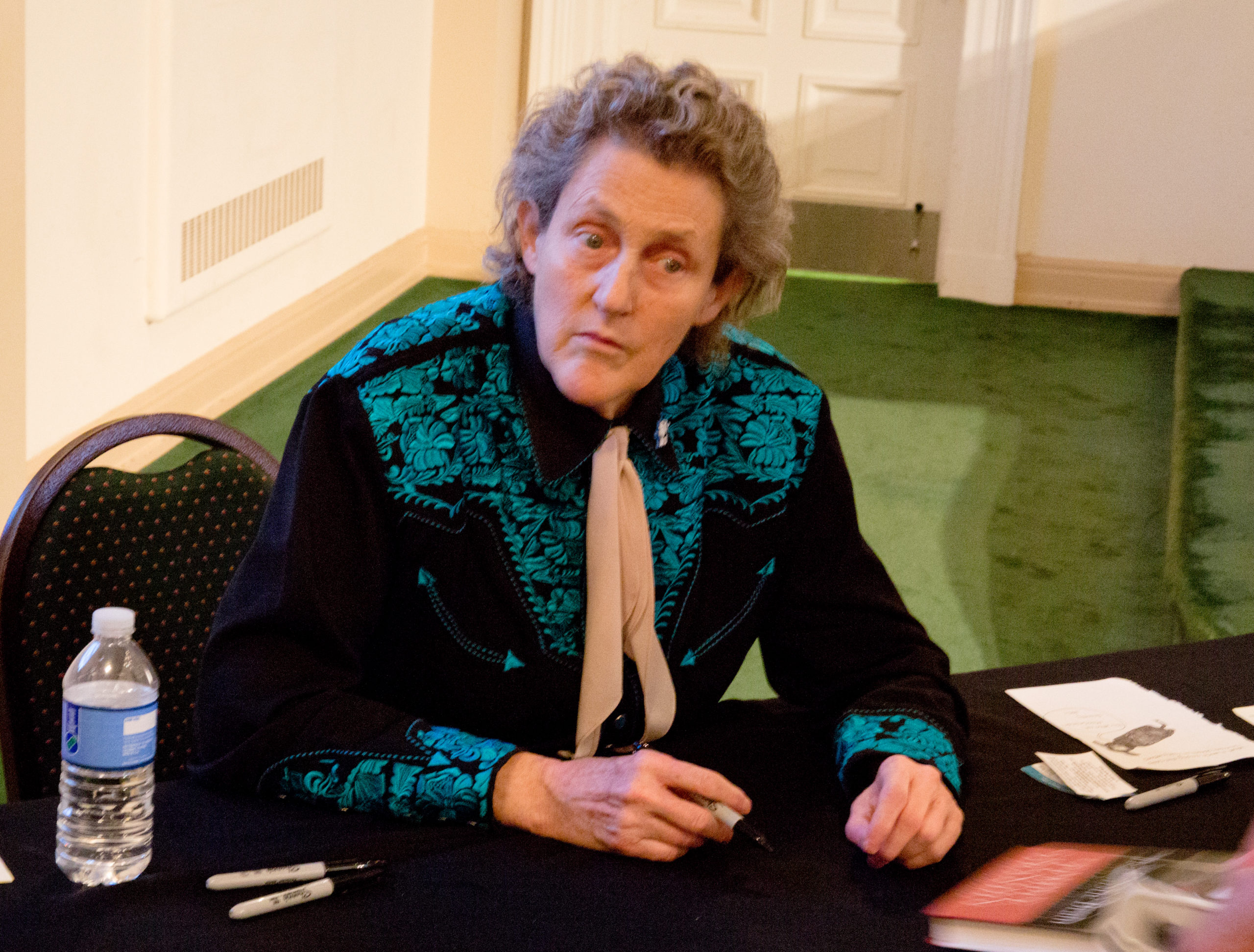 The autism Activist Temple Grandin looks in a certain direction as she holds a pen in her hand. 