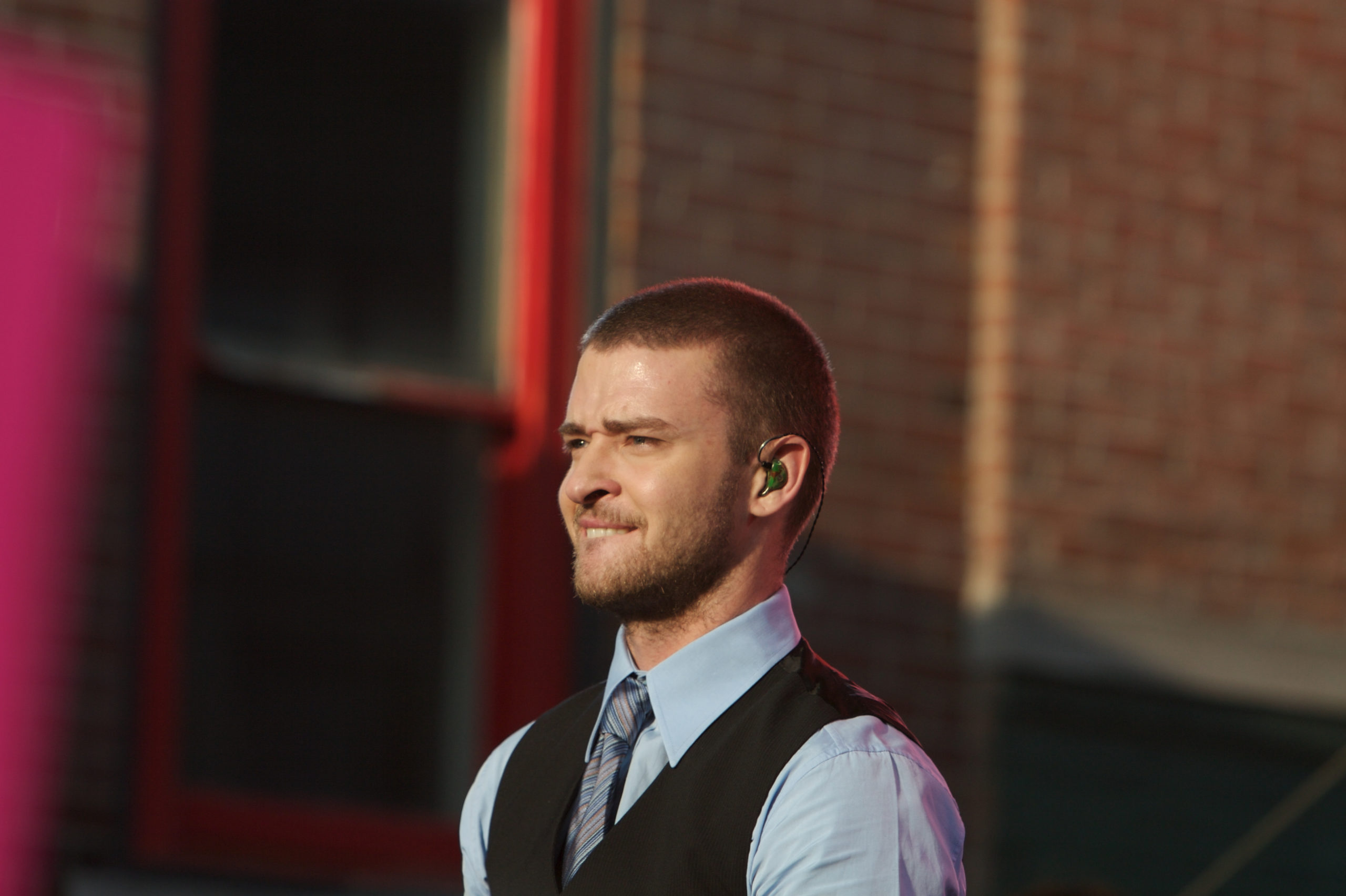Justin TImberlake smiles as he stands in front of a brick wall.