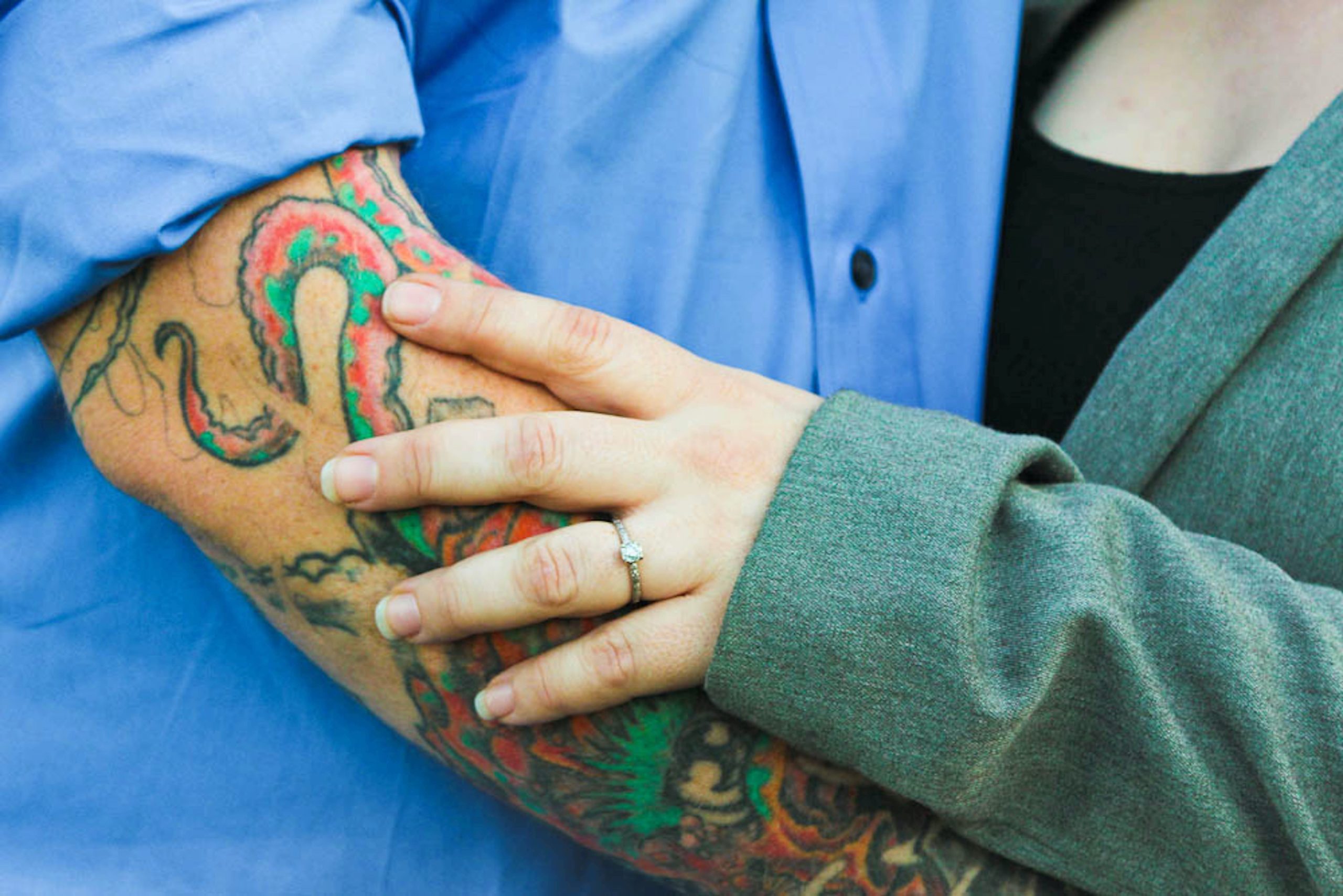 A woman is touching a man's tattooed arm.