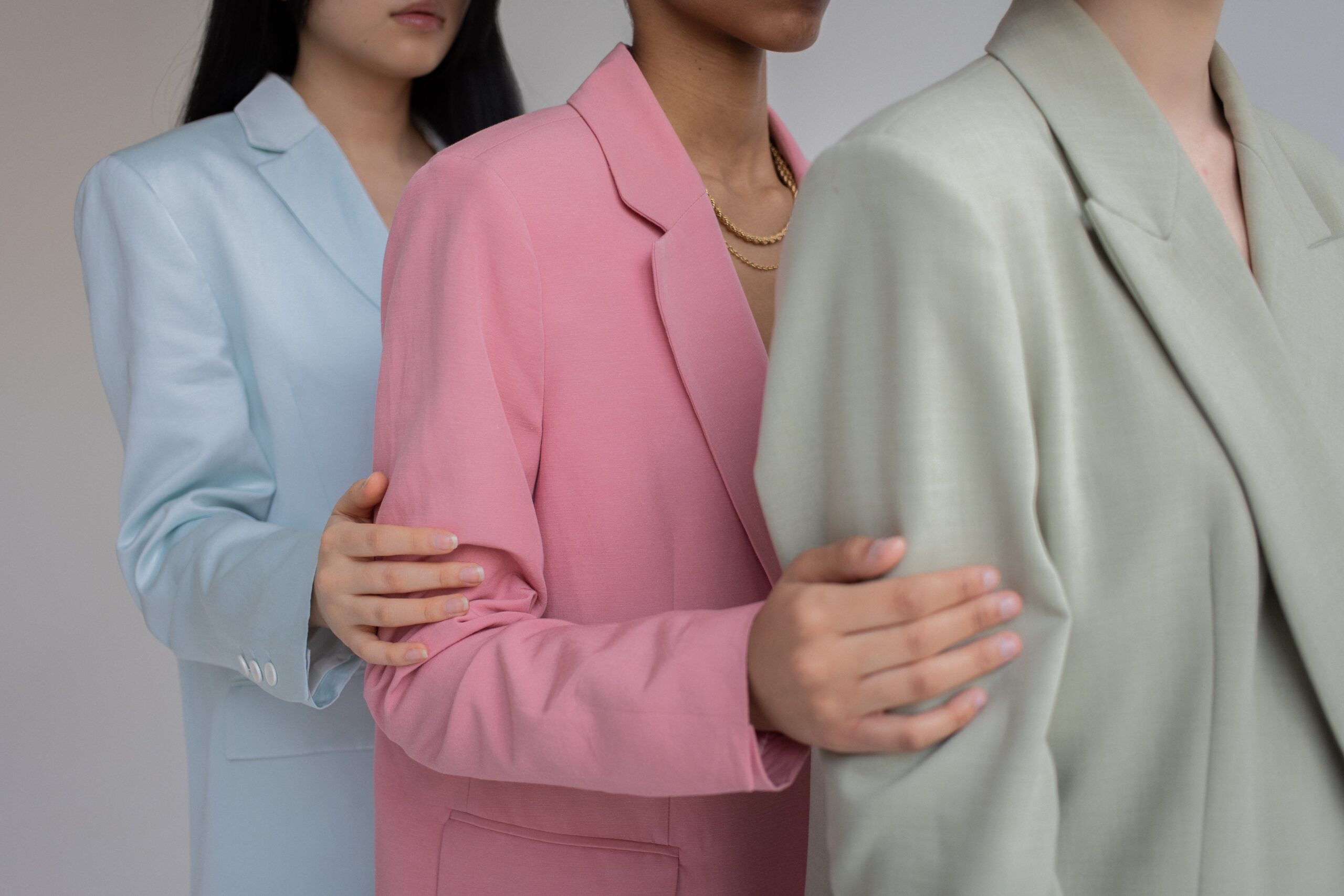 Mid-shot of 3 women wearing different coloured suits