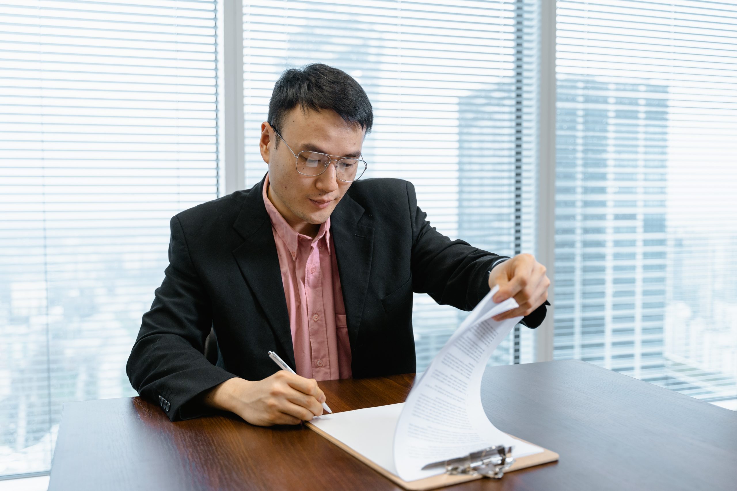 A man is looking through several sheets of paper on a clipboard.