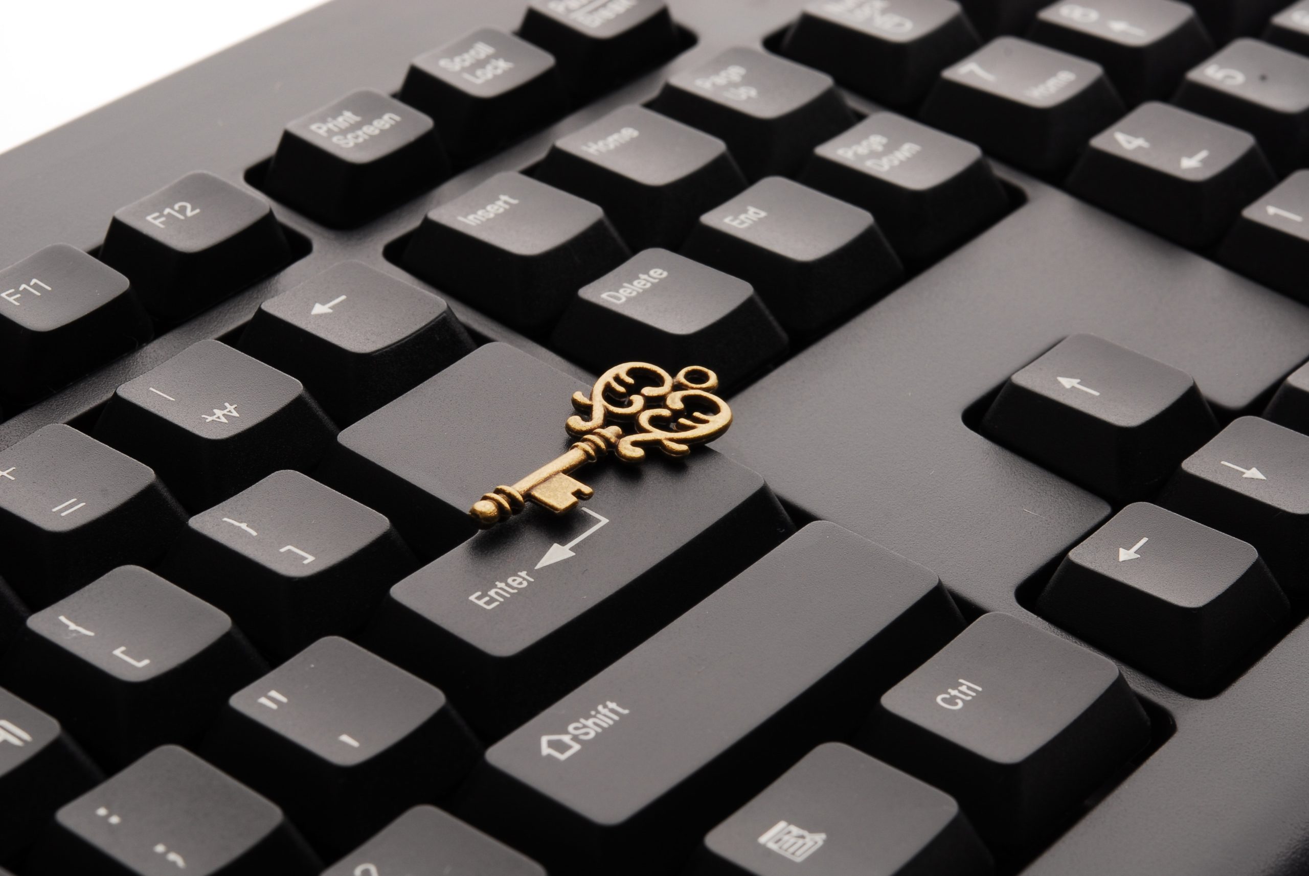 A golden key lies on a black computer keyboard.