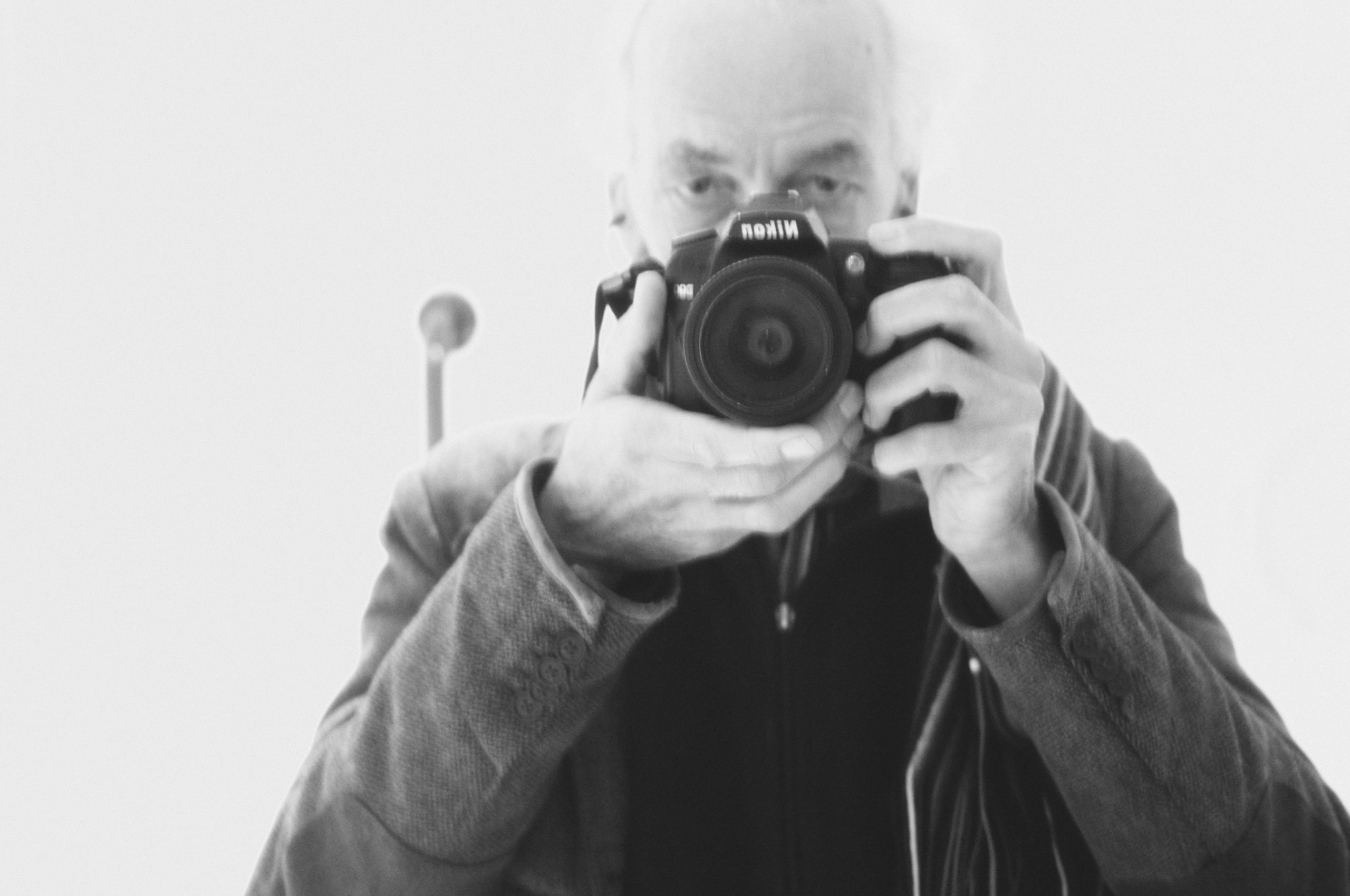 A black and white photograph of the photographer David Bailey holding a camera.