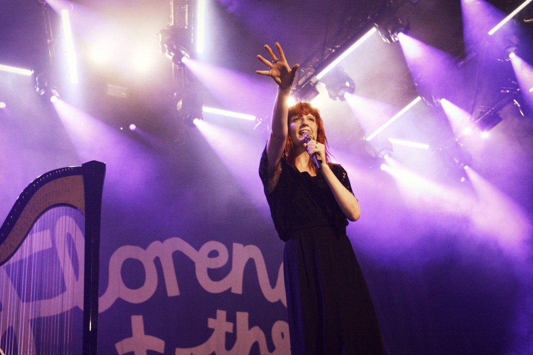 Florence Welch, lead singer of Florence + the Machine, is performing on a stage.