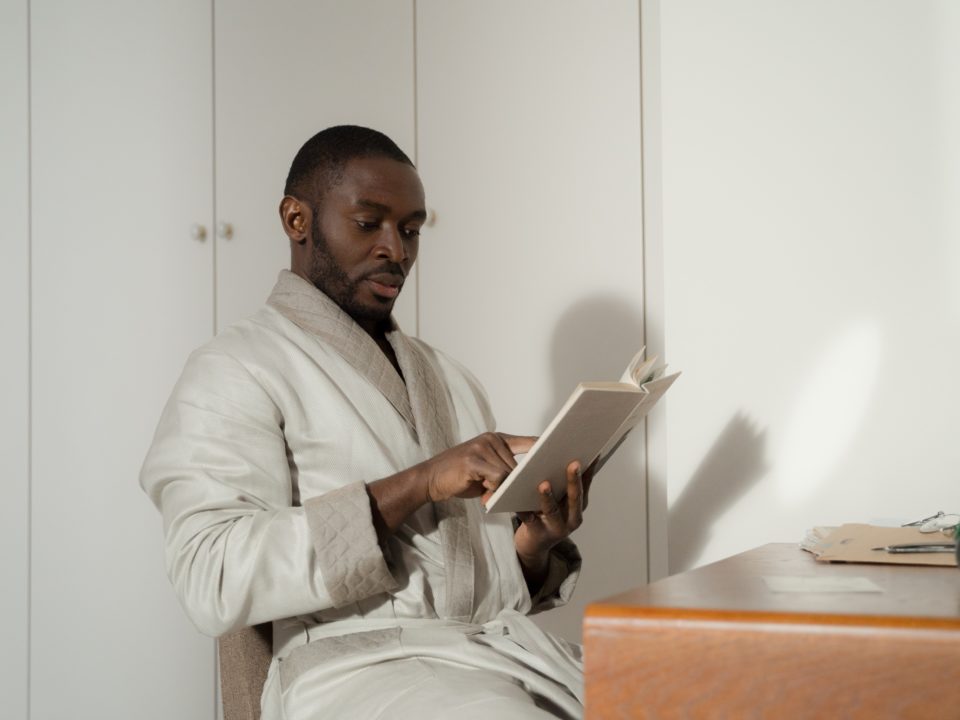 A man is sitting at a table and reading a book.