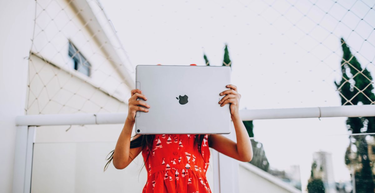 A girl is hiding a face behind a big iPad.