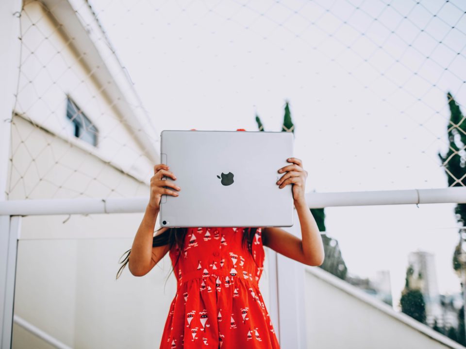 A girl is hiding a face behind a big iPad.