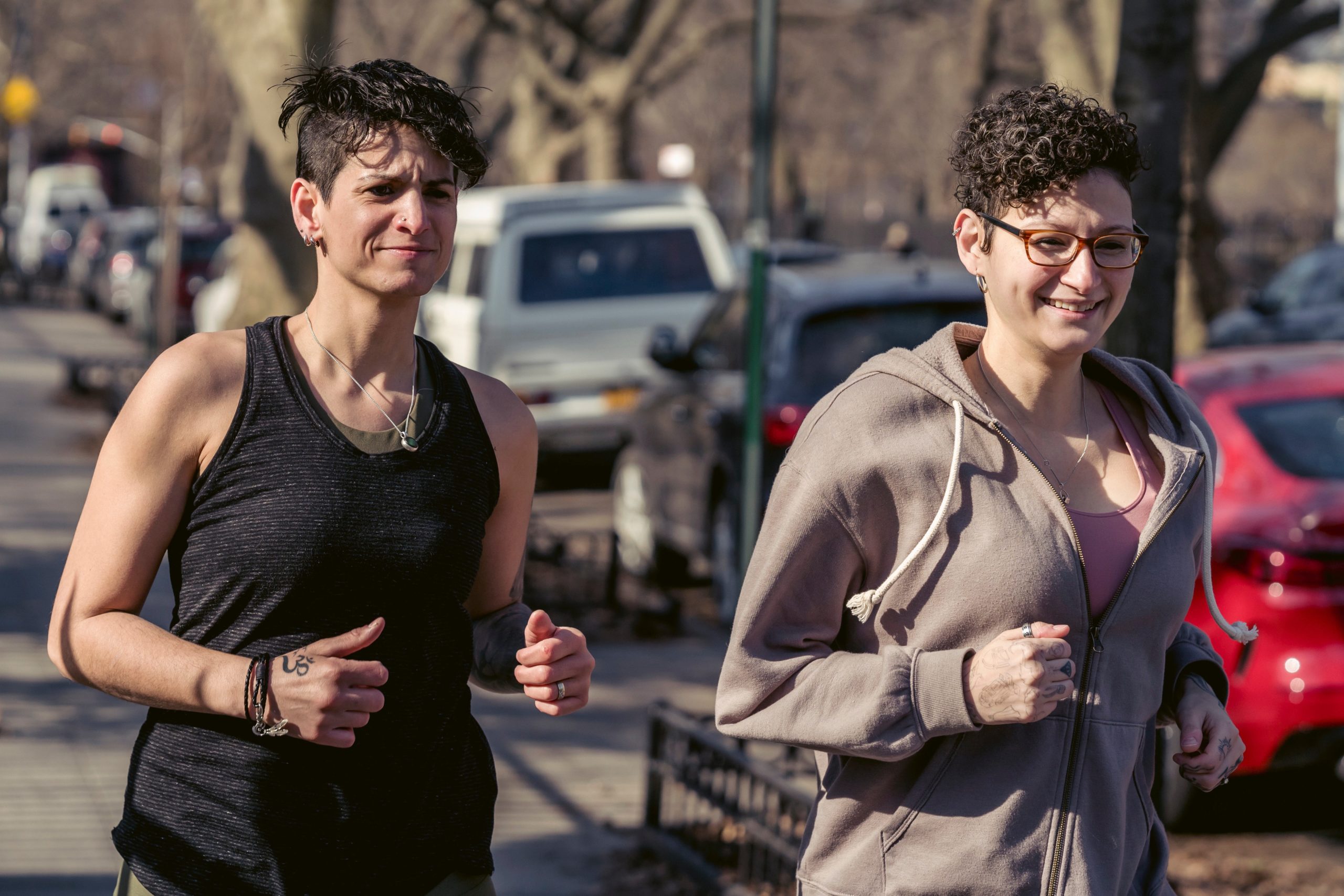 Two androgynous-looking women are jogging down a street.