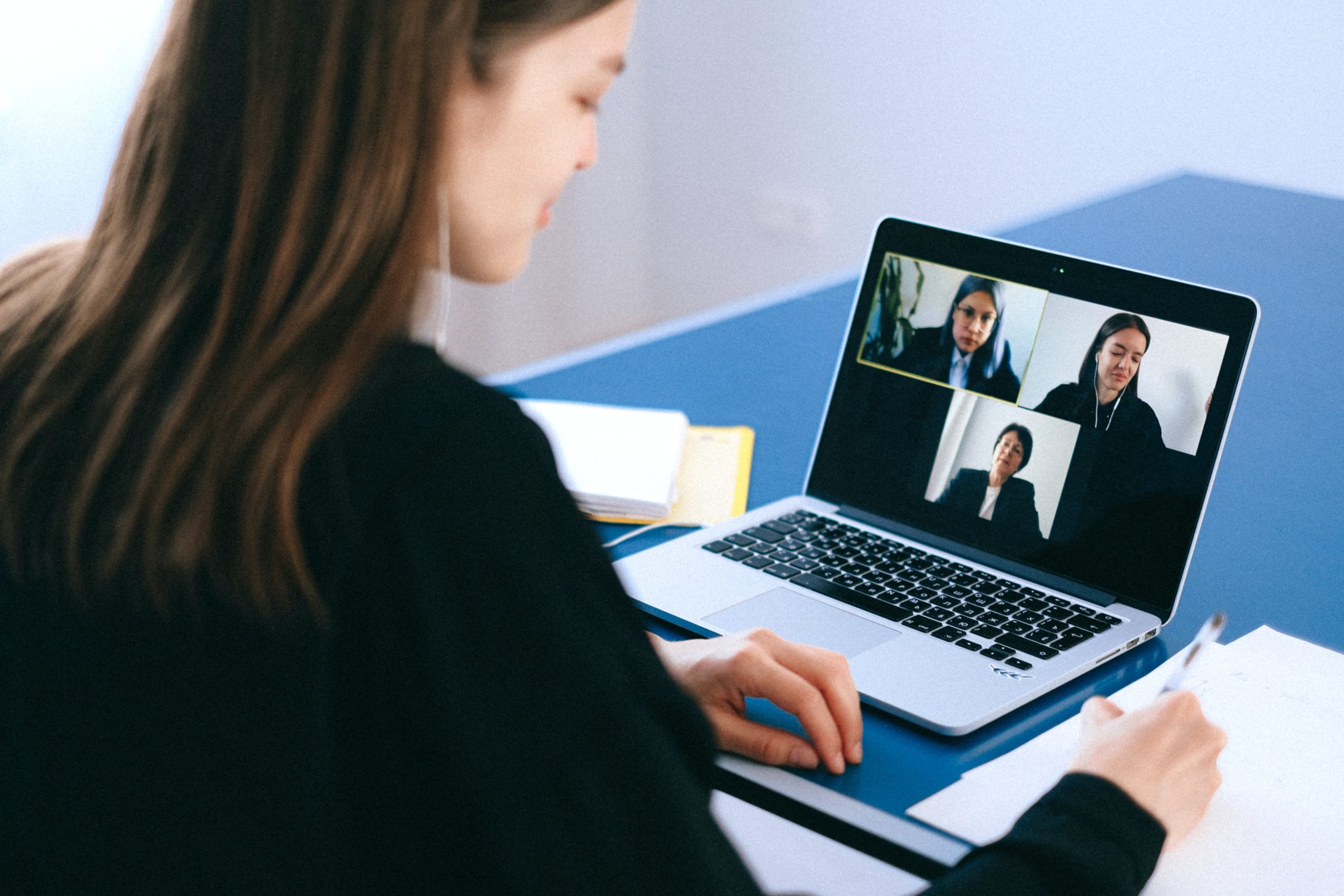 A woman is taking part in a video call with three other people.