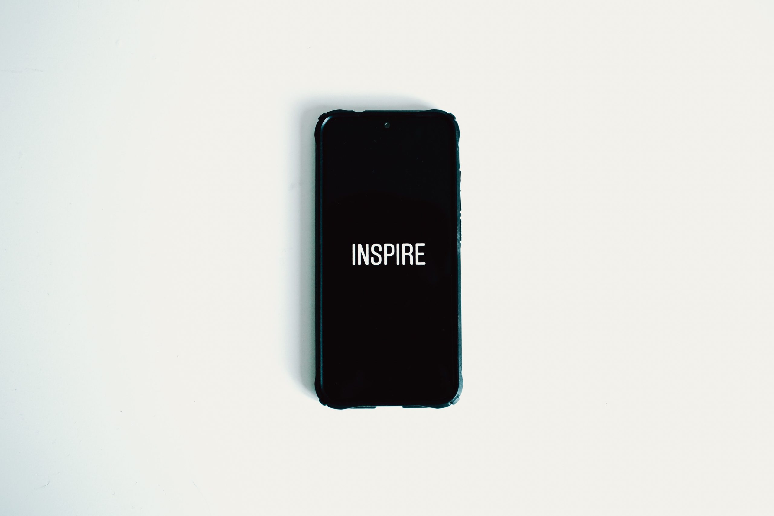 A smartphone that says, "INSPIRE," lies on a white surface.