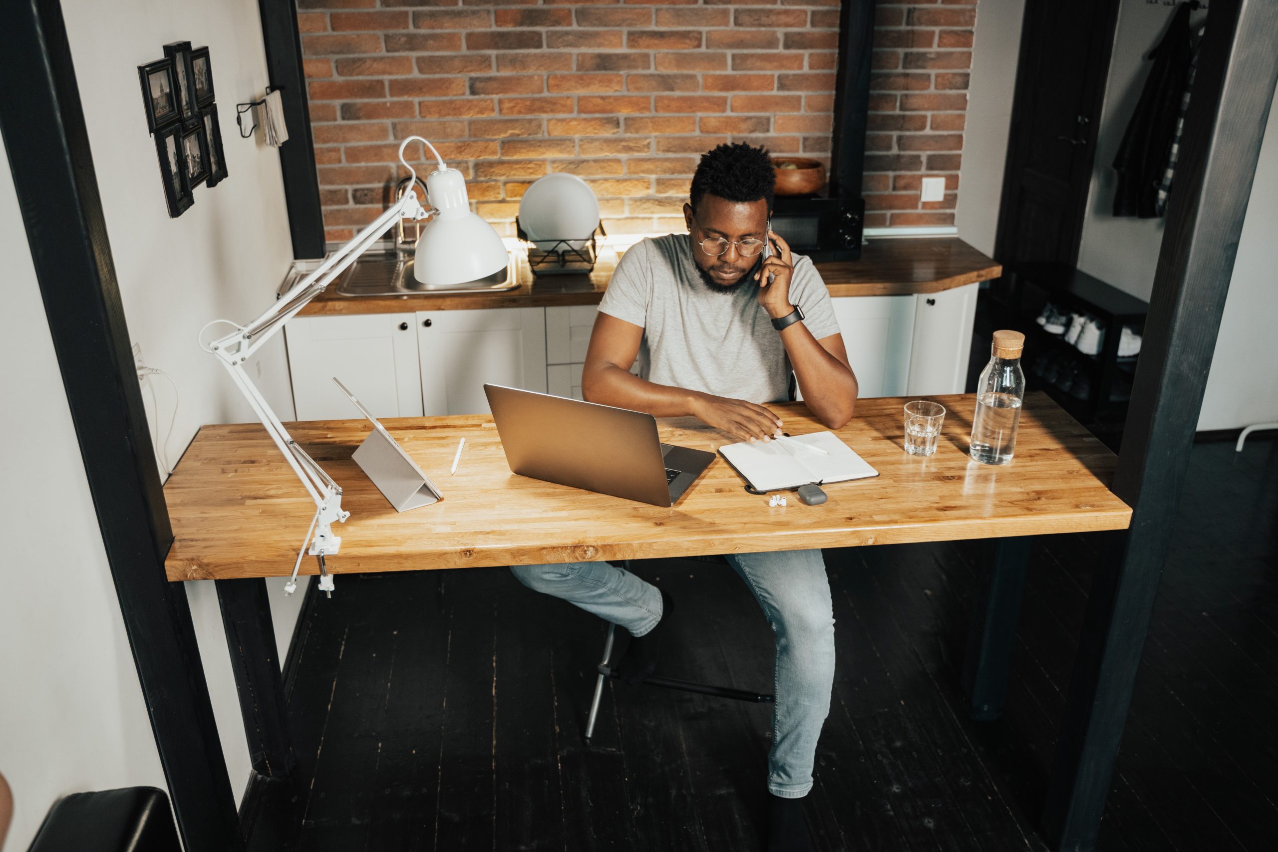 An Afro-Caribbean man is working at his desk in a homely setting. 