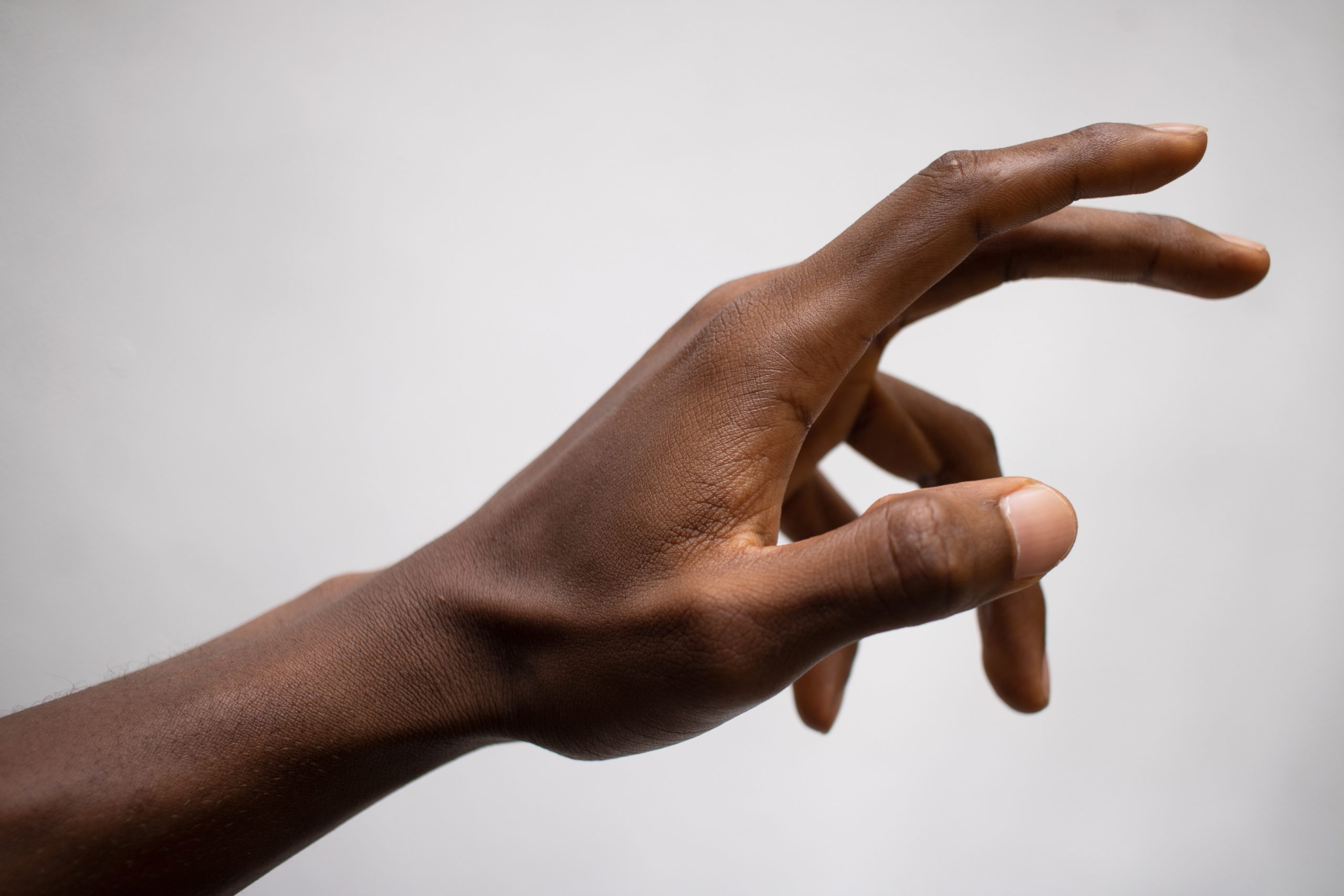 A black hand is being held up in front of a white background.