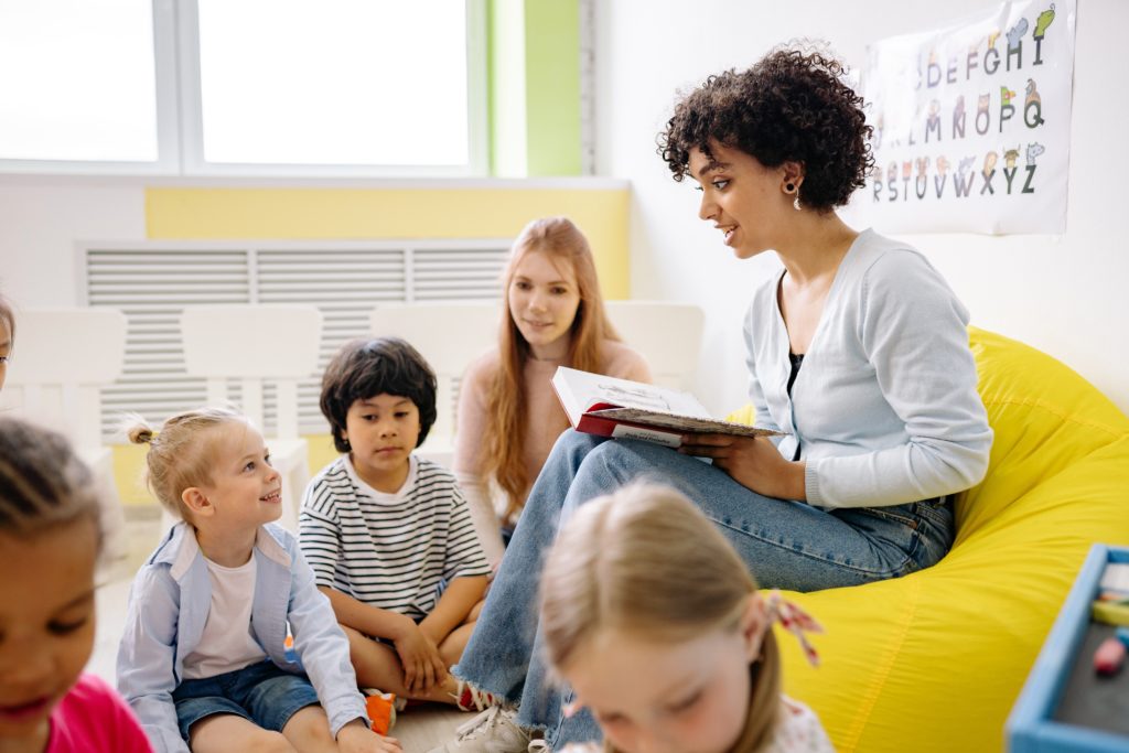 A woman is reading a story to some children.