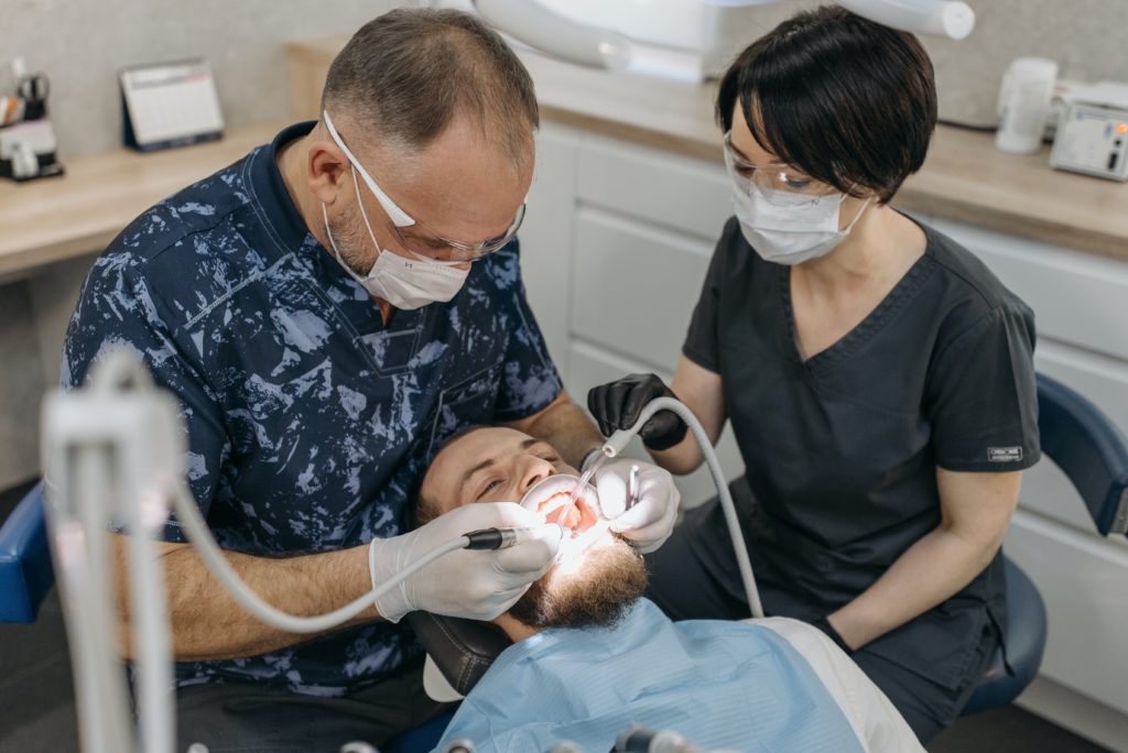 Two dental assistants are carrying out dental work on a patient.