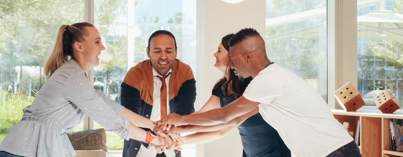 Four people are stacking their hands on top of each other.