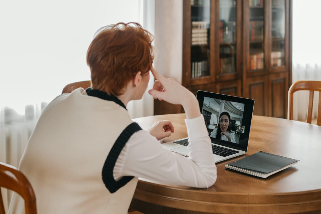 A person is having a video call with another on a laptop screen.