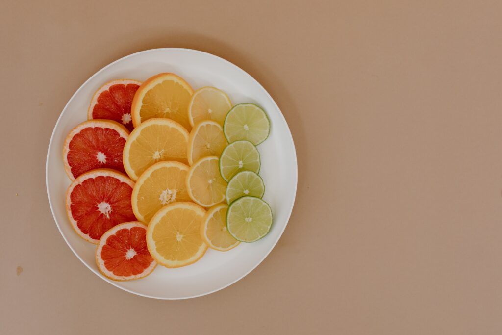 Slices of four different types of citrus fruit lie on a plate.