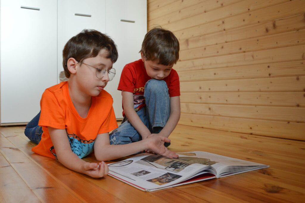 Two boys are looking inside a photo book.