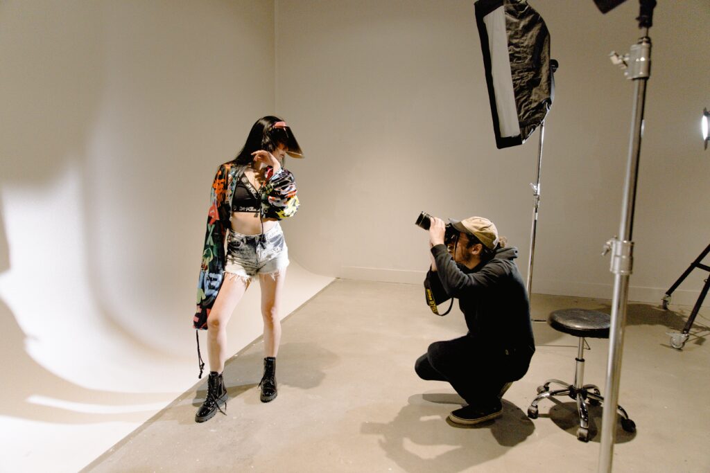 A man photographs a woman in a photography studio.