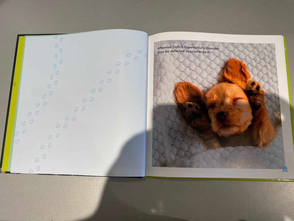 An open page of All Dogs Have ADHD shows a puppy lying in some bedding. The text reads, "Attention Deficit Hyperactivity Disorder may be detected soon after birth."