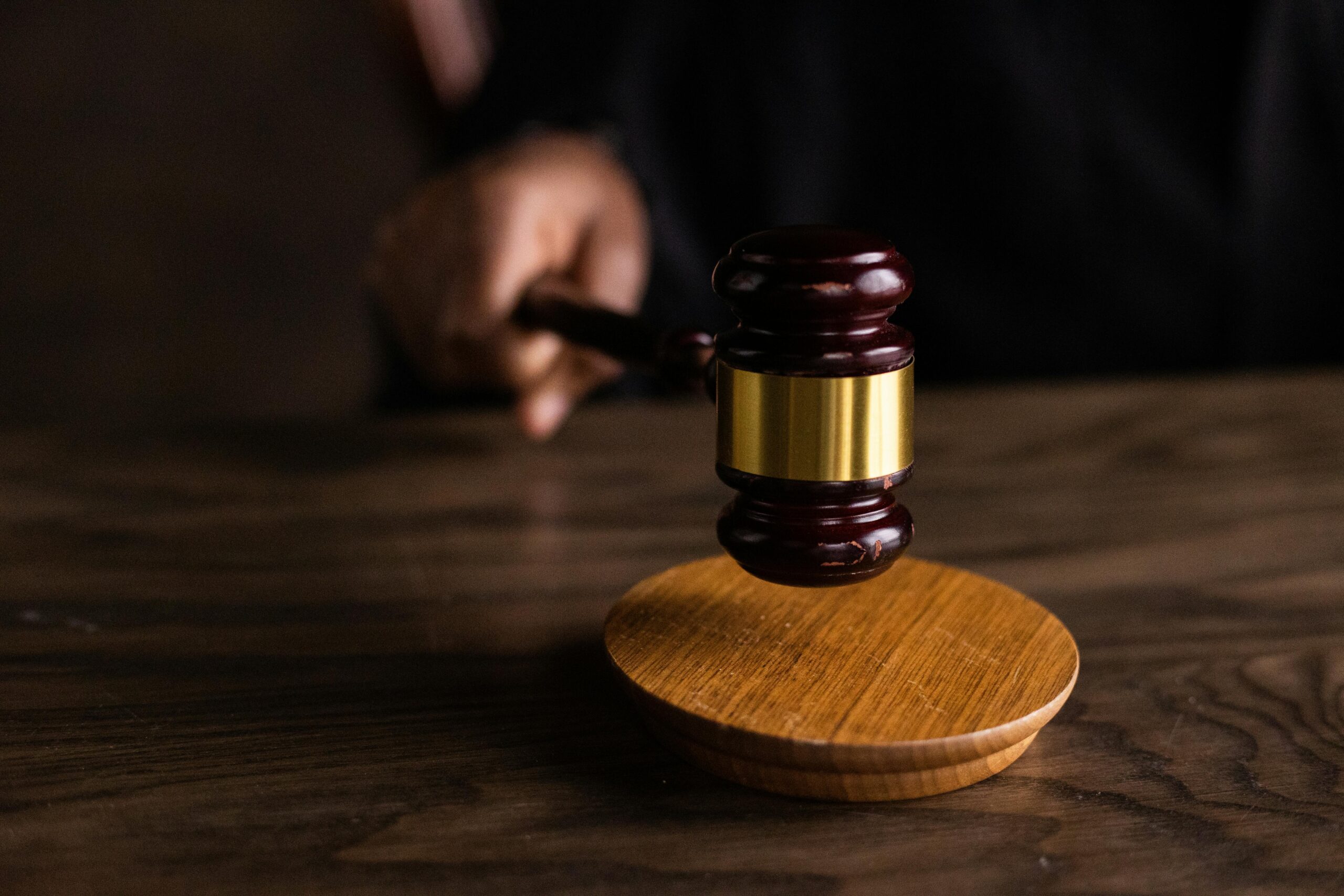 A close-up of a person's hand holding a gavel on a table.