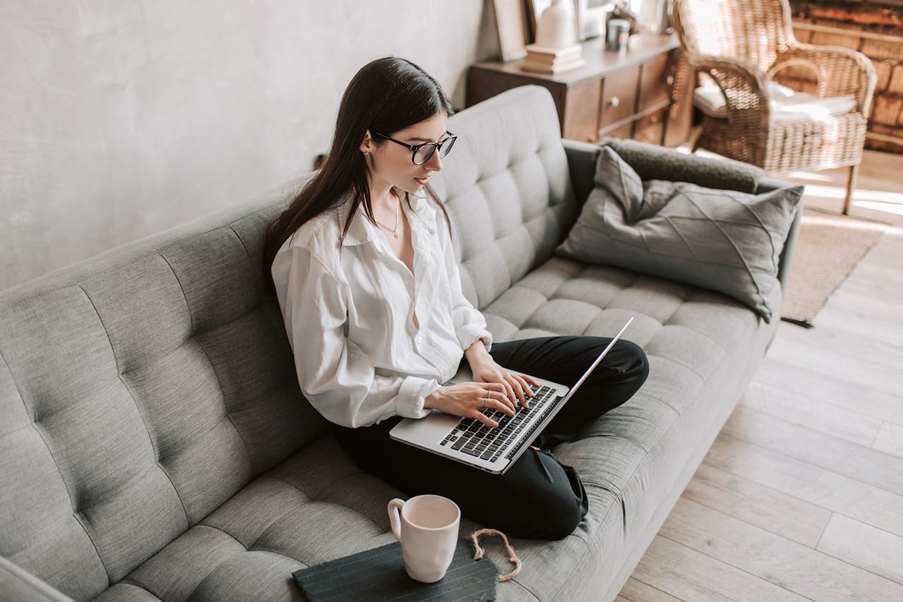 Alt text: Woman working comfortably from home on a laptop in a cozy setting