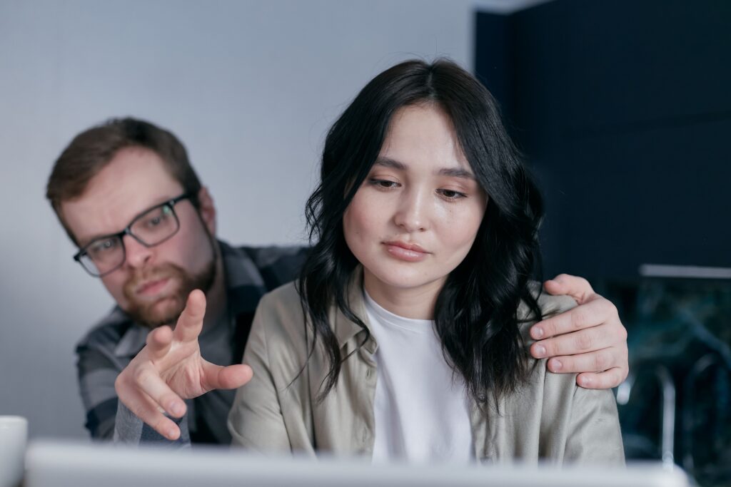Two colleagues looking at a computer while discussing inclusive workplace practices.